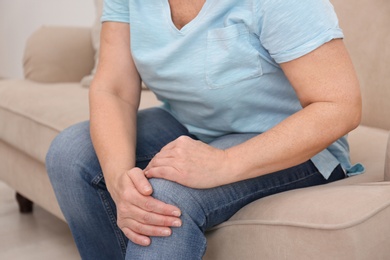 Photo of Senior woman suffering from knee pain at home, closeup