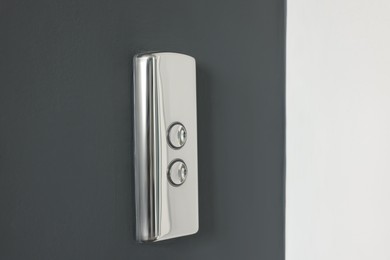 Elevator call buttons on grey wall, closeup