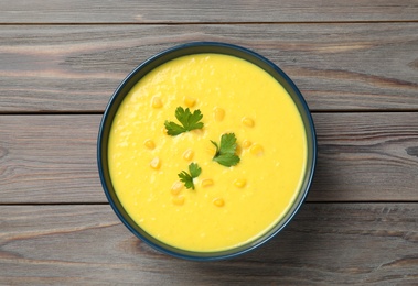 Photo of Delicious creamy corn soup served on wooden table, top view