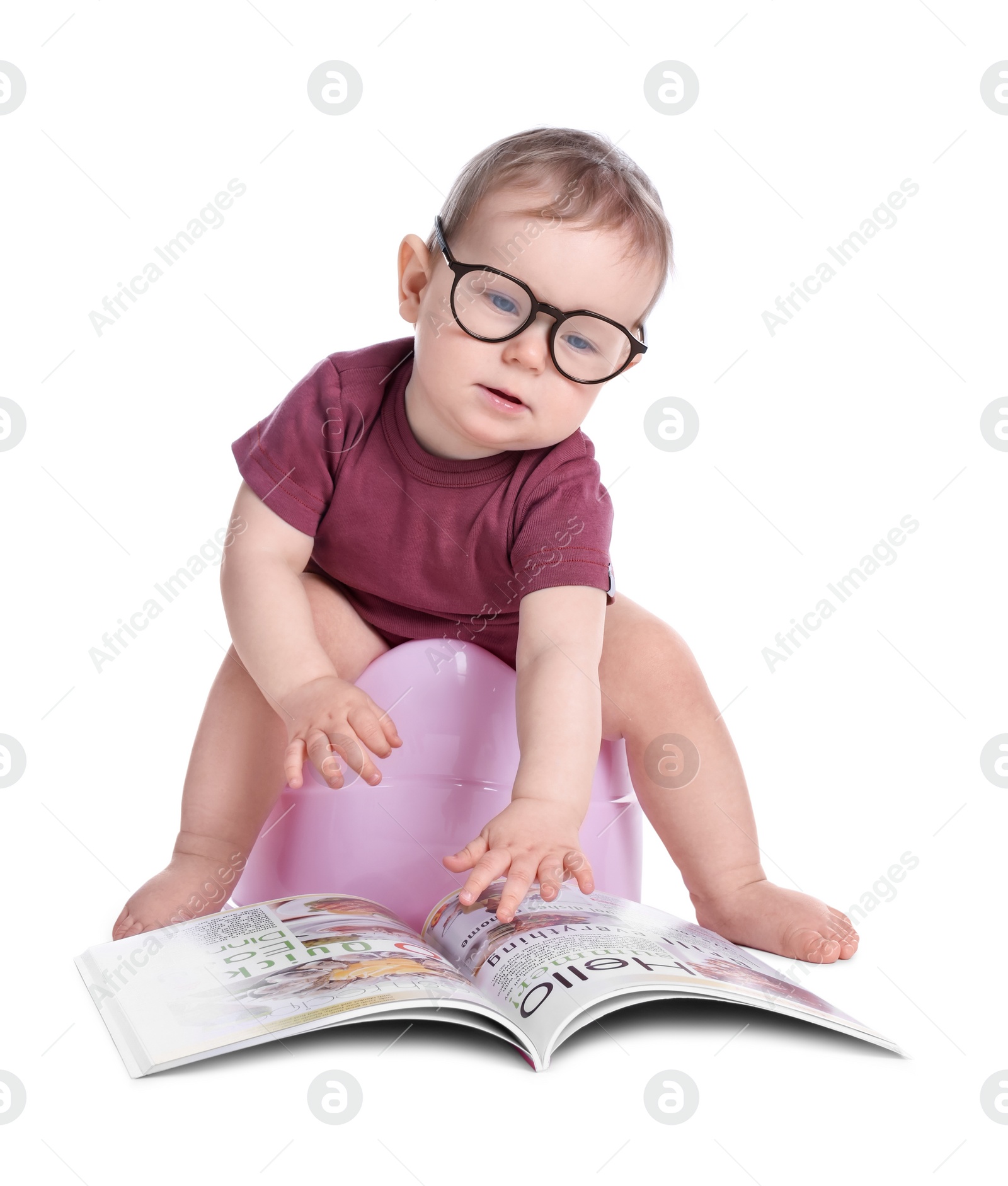 Photo of Little child with glasses and book sitting on baby potty against white background