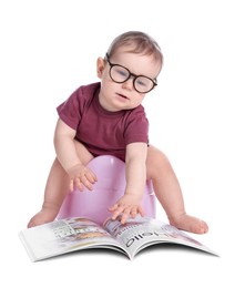 Photo of Little child with glasses and book sitting on baby potty against white background