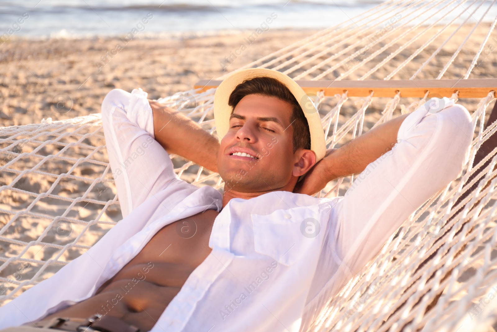 Photo of Man relaxing in hammock on beach. Summer vacation