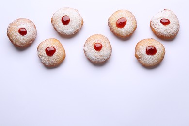 Photo of Hanukkah donuts with jelly and powdered sugar on white background, flat lay. Space for text