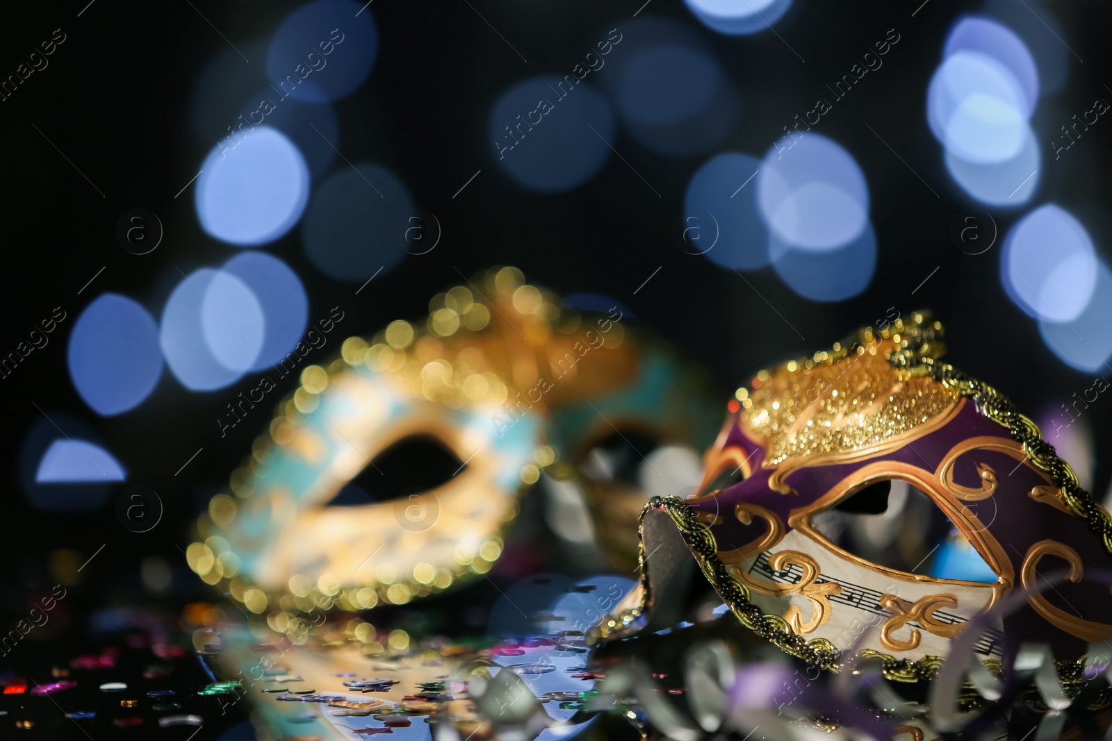 Photo of Beautiful carnival mask on table against blurred lights. Space for text