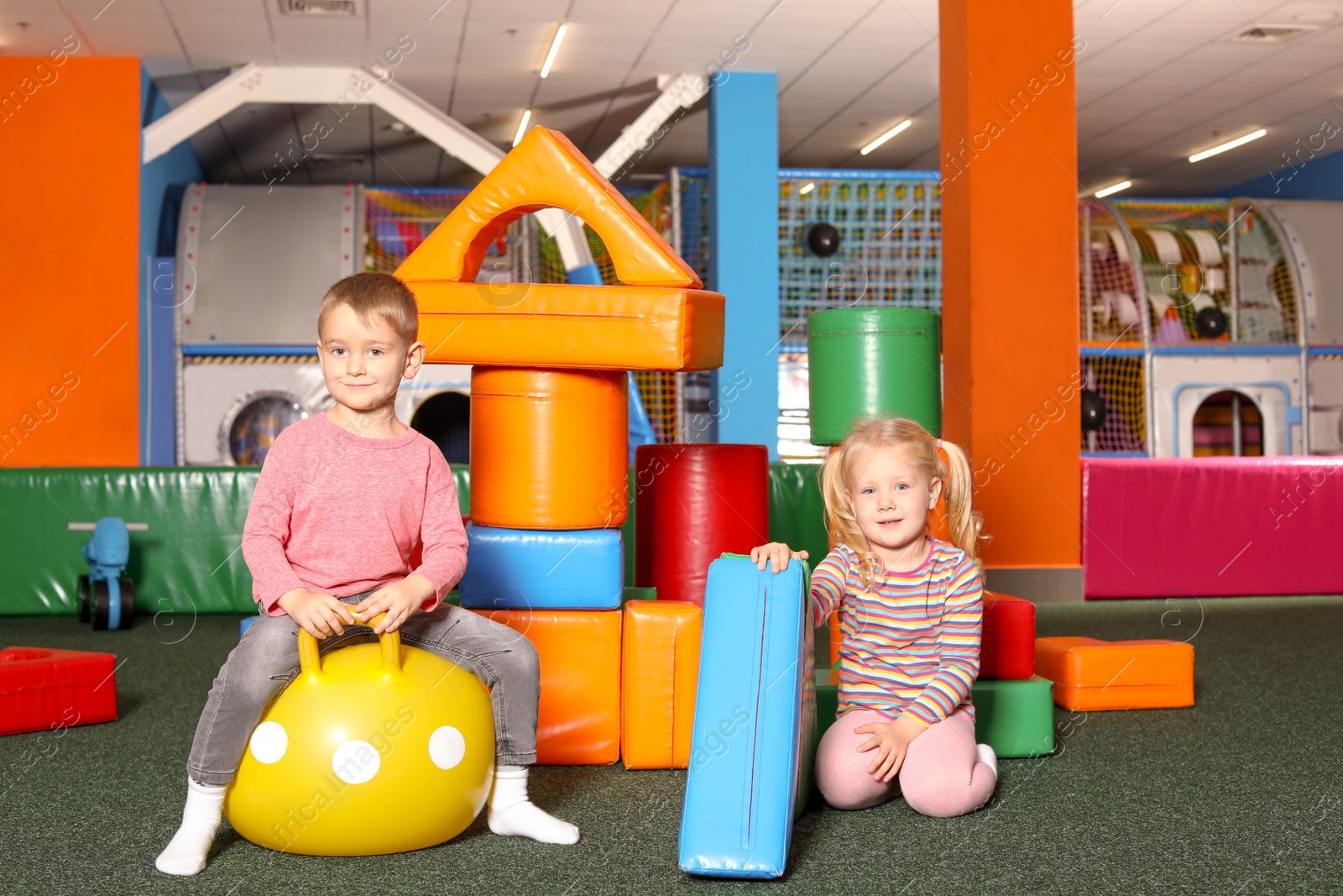 Photo of Cute children playing with ball and colorful building blocks indoors