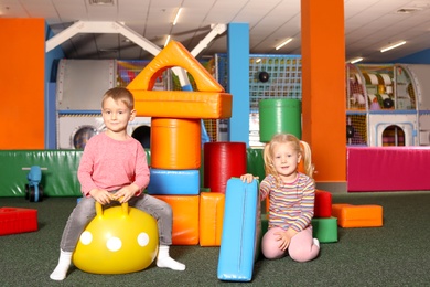 Photo of Cute children playing with ball and colorful building blocks indoors