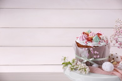 Photo of Traditional Easter cake with meringues and painted eggs on white wooden table, space for text