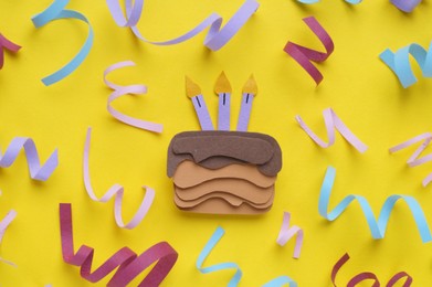 Birthday party. Paper cake and confetti on yellow background, flat lay
