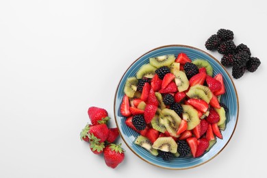 Plate of yummy fruit salad and ingredients on light blue background, flat lay. Space for text