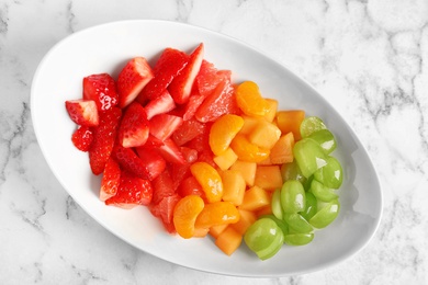 Plate with fresh cut fruits on table, top view