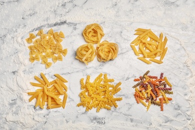 Flat lay composition with different uncooked pasta on table