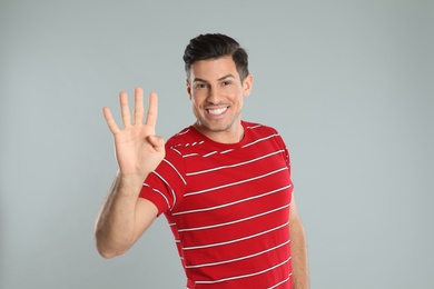 Photo of Man showing number four with his hand on grey background