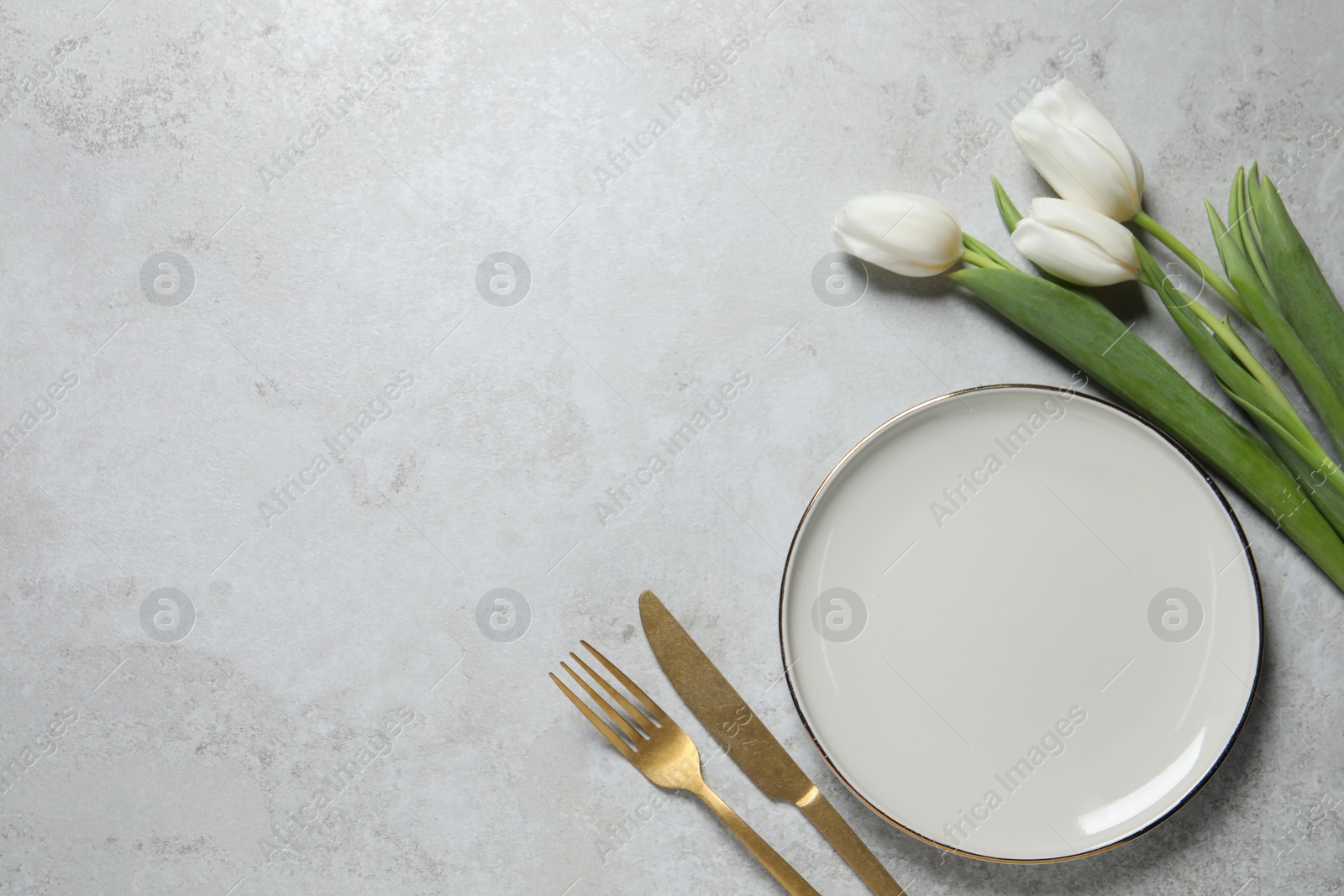 Photo of Stylish table setting with cutlery and flowers on grey background, flat lay. Space for text