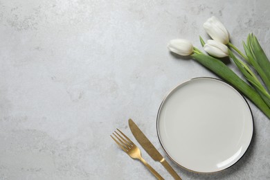 Stylish table setting with cutlery and flowers on grey background, flat lay. Space for text