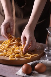 Photo of Woman making homemade pasta at wooden table, closeup