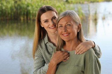 Family portrait of happy mother and daughter spending time together near pond