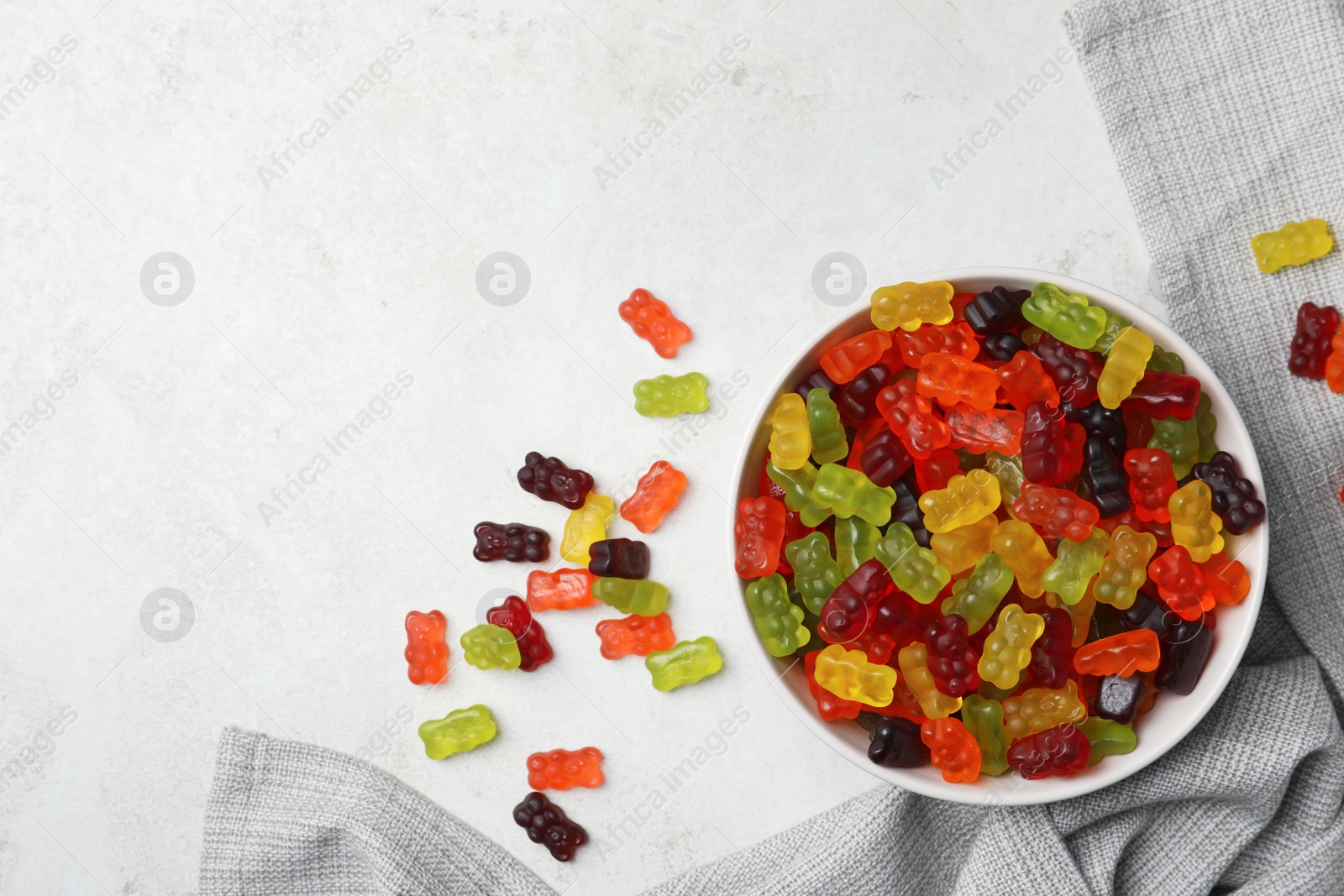 Photo of Delicious gummy bear candies on light table, flat lay. Space for text