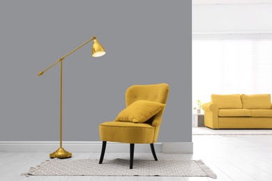 Image of Color of the year 2021. Stylish yellow armchair with cushion, rug and lamp indoors