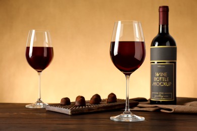 Photo of Bottle and glasses of red wine with chocolate candies on wooden table