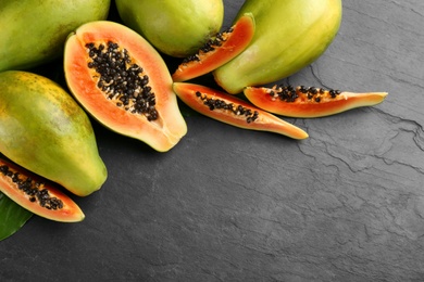 Photo of Fresh ripe papaya fruits on black table, flat lay. Space for text