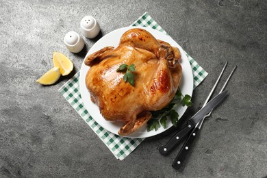 Tasty roasted chicken with parsley served on grey textured table, flat lay