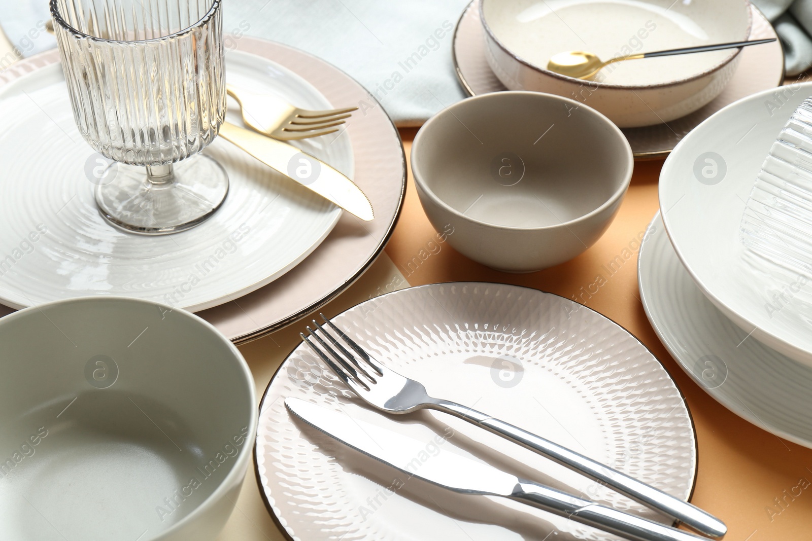 Photo of Clean plates, bowls, glass and cutlery on table