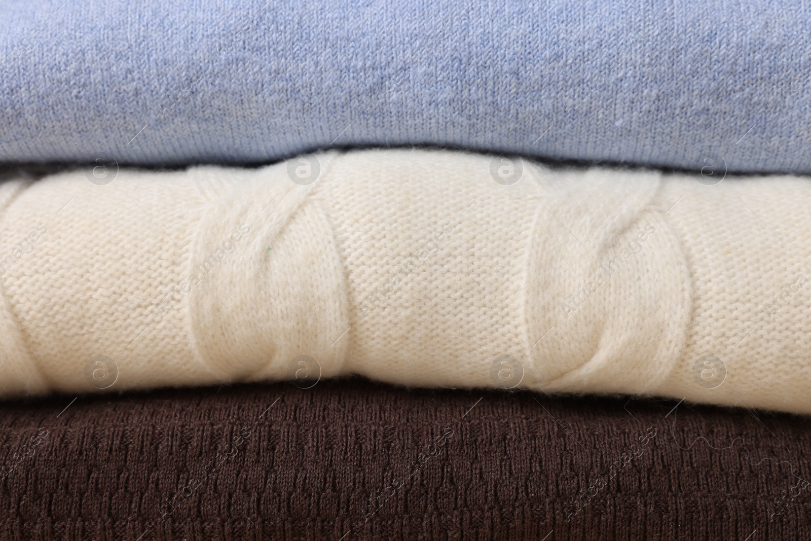 Photo of Stack of casual warm sweaters as background, closeup view