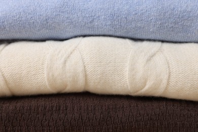 Stack of casual warm sweaters as background, closeup view