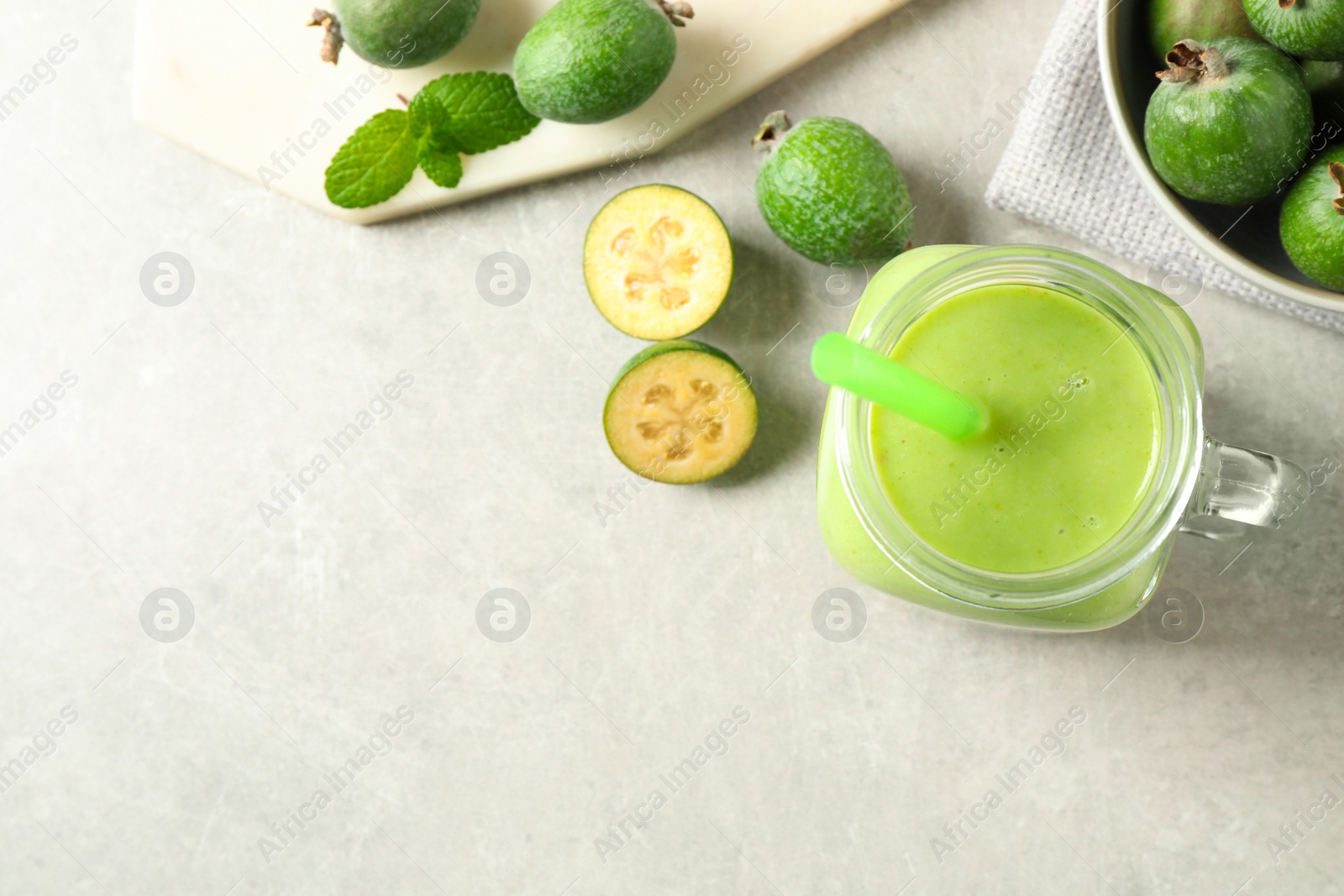 Photo of Fresh feijoa smoothie and fresh fruits on light table, flat lay. Space for text