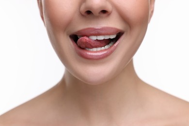Photo of Woman with beautiful lips licking her teeth on white background, closeup