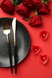 Photo of Place setting with heart shaped candles and bouquet of roses on red table, flat lay. Romantic dinner