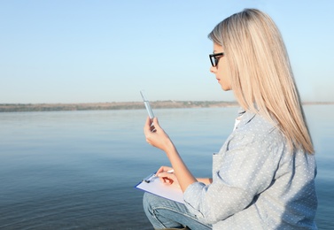 Scientist with clipboard and sample taken from river