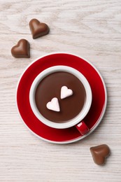 Photo of Cup of hot chocolate with heart shaped marshmallows and candies on white wooden table, flat lay