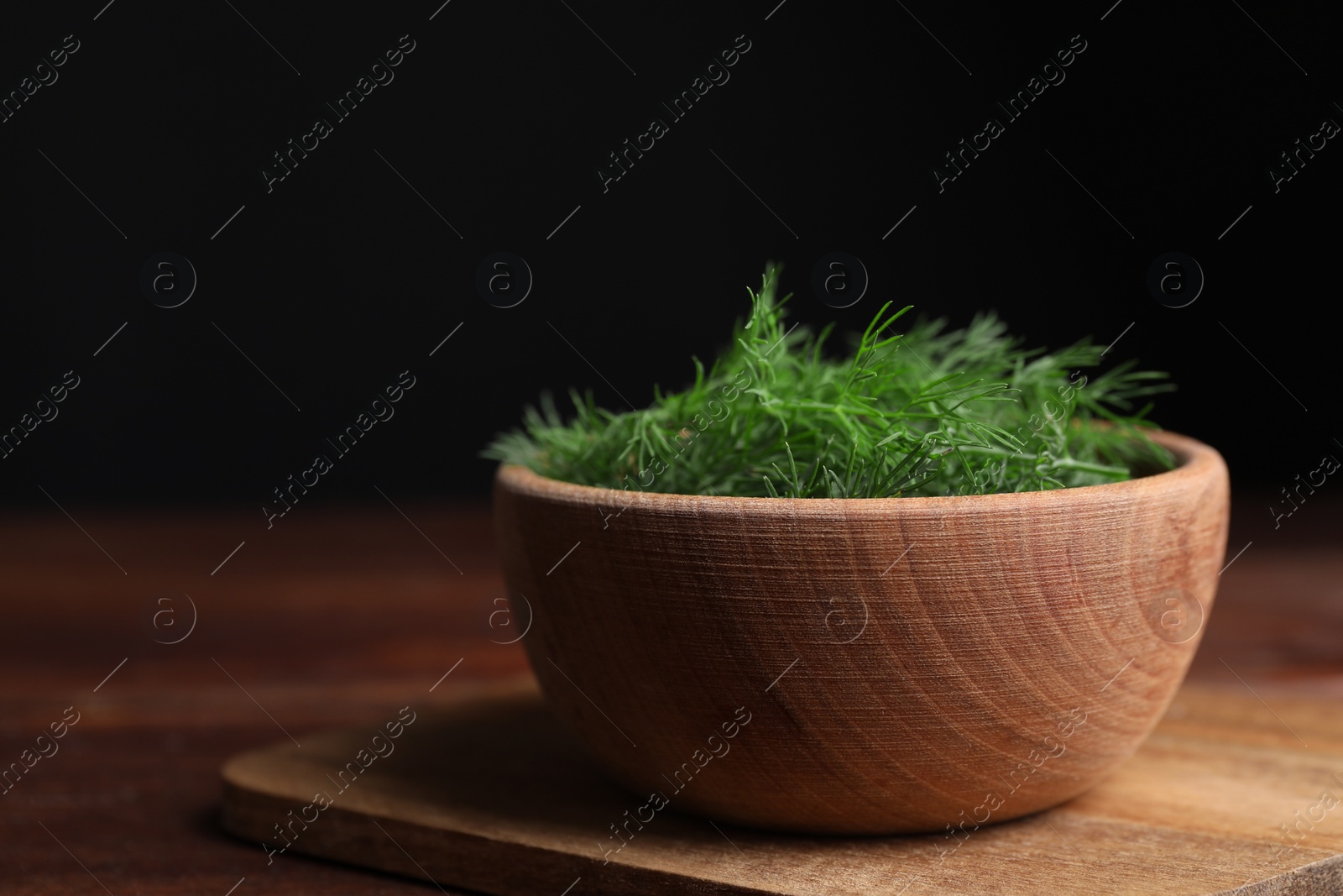 Photo of Bowl of fresh dill on wooden table, closeup. Space for text