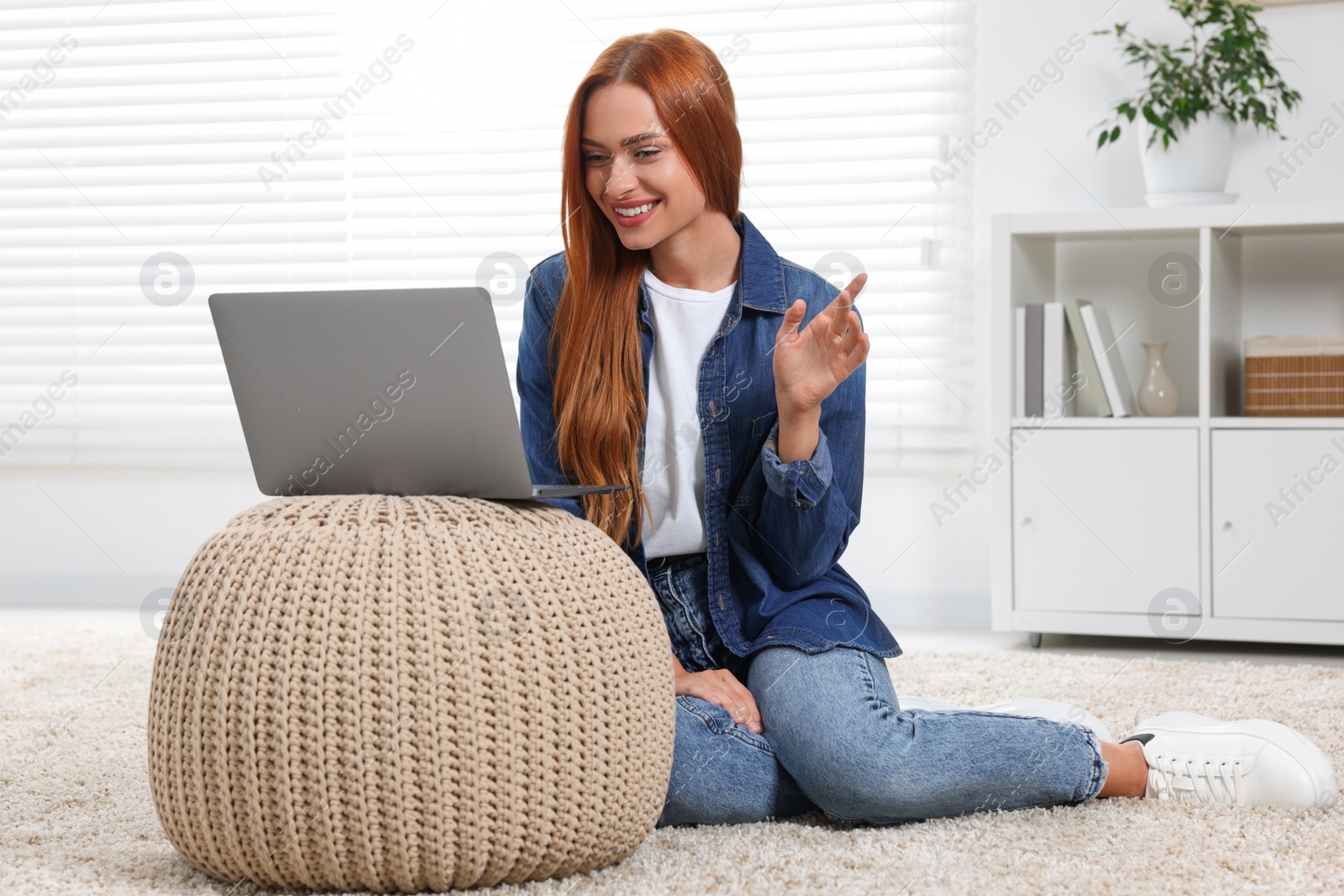 Photo of Woman waving hello during video chat via laptop at home