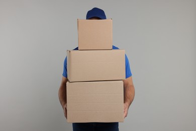Photo of Courier with stack of parcels on grey background