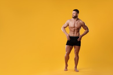 Photo of Young man is stylish black underwear on orange background