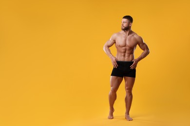 Young man is stylish black underwear on orange background