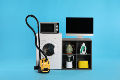 Photo of Set of different home appliances with vacuum cleaner on light blue background