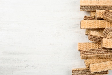 Photo of Delicious crispy wafers on white wooden table, top view. Space for text