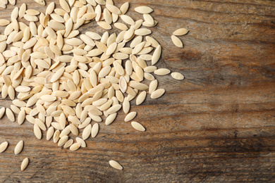 Photo of Raw cucumber seeds on wooden background, flat lay. Vegetable planting