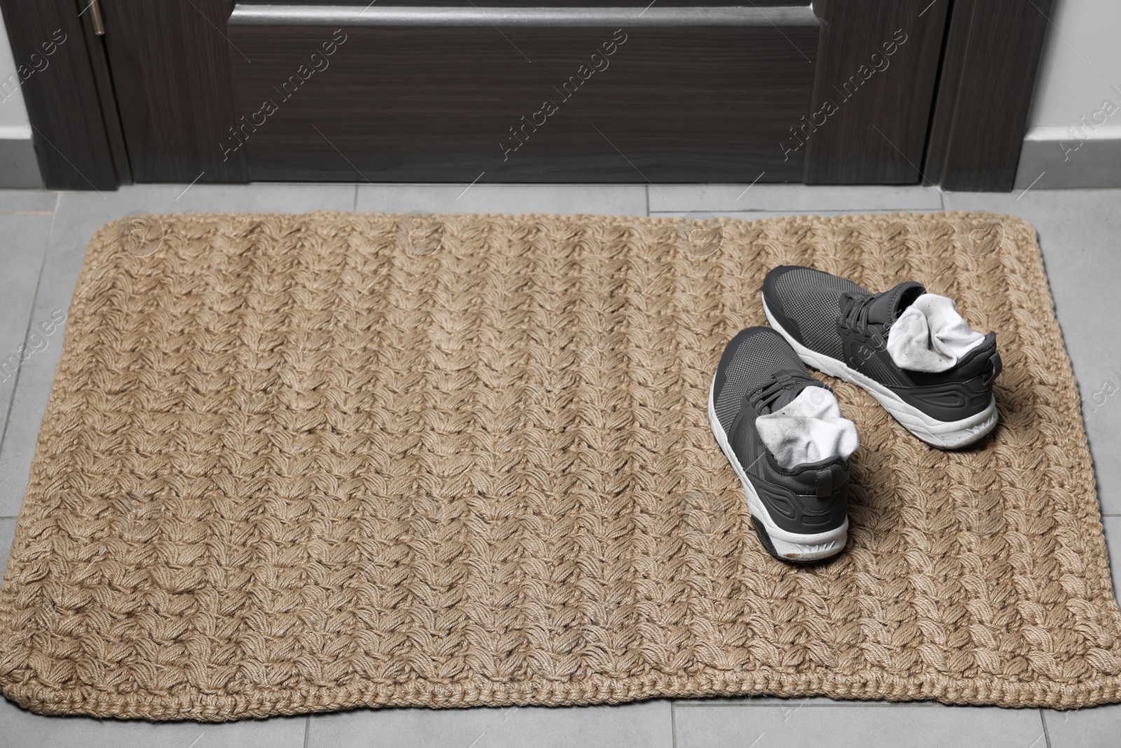 Photo of Sneakers with dirty socks on woven mat indoors, closeup. Space for text