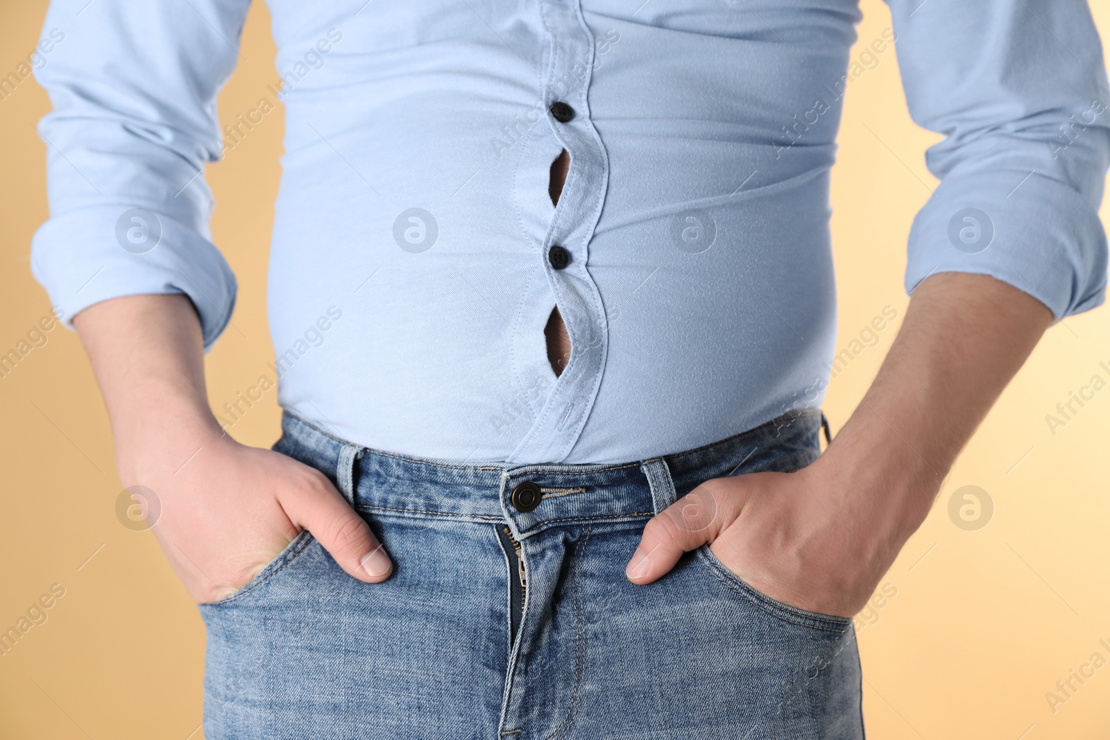 Photo of Overweight man in tight shirt on yellow background, closeup