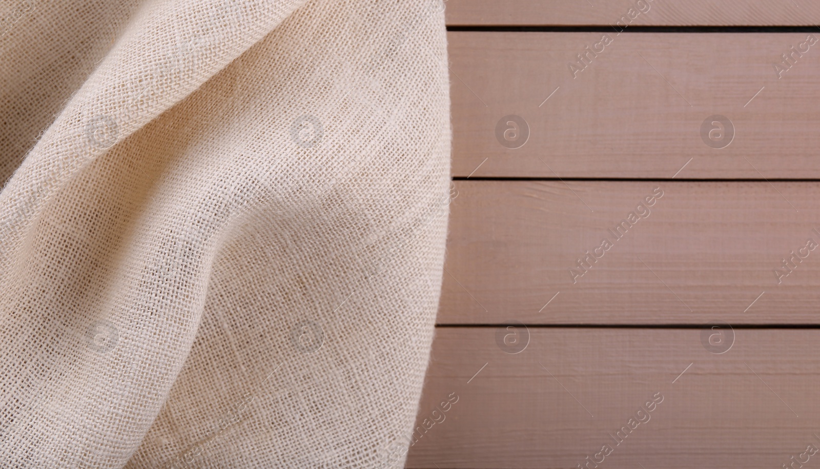 Photo of Beige burlap fabric on wooden table, top view. Space for text