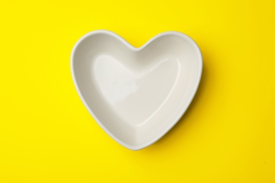 Photo of Heart shaped plate on color background, top view