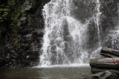 Picturesque view of beautiful mountain waterfall and rocks outdoors