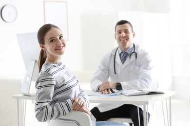 Photo of Doctor consulting patient at desk in clinic