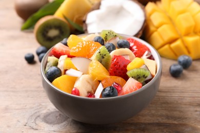 Photo of Delicious fresh fruit salad in bowl on wooden table