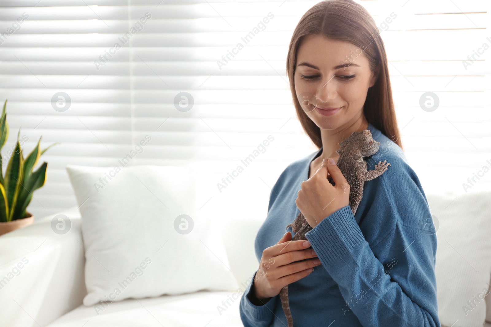 Photo of Young woman with bearded lizard at home, space for text. Exotic pet