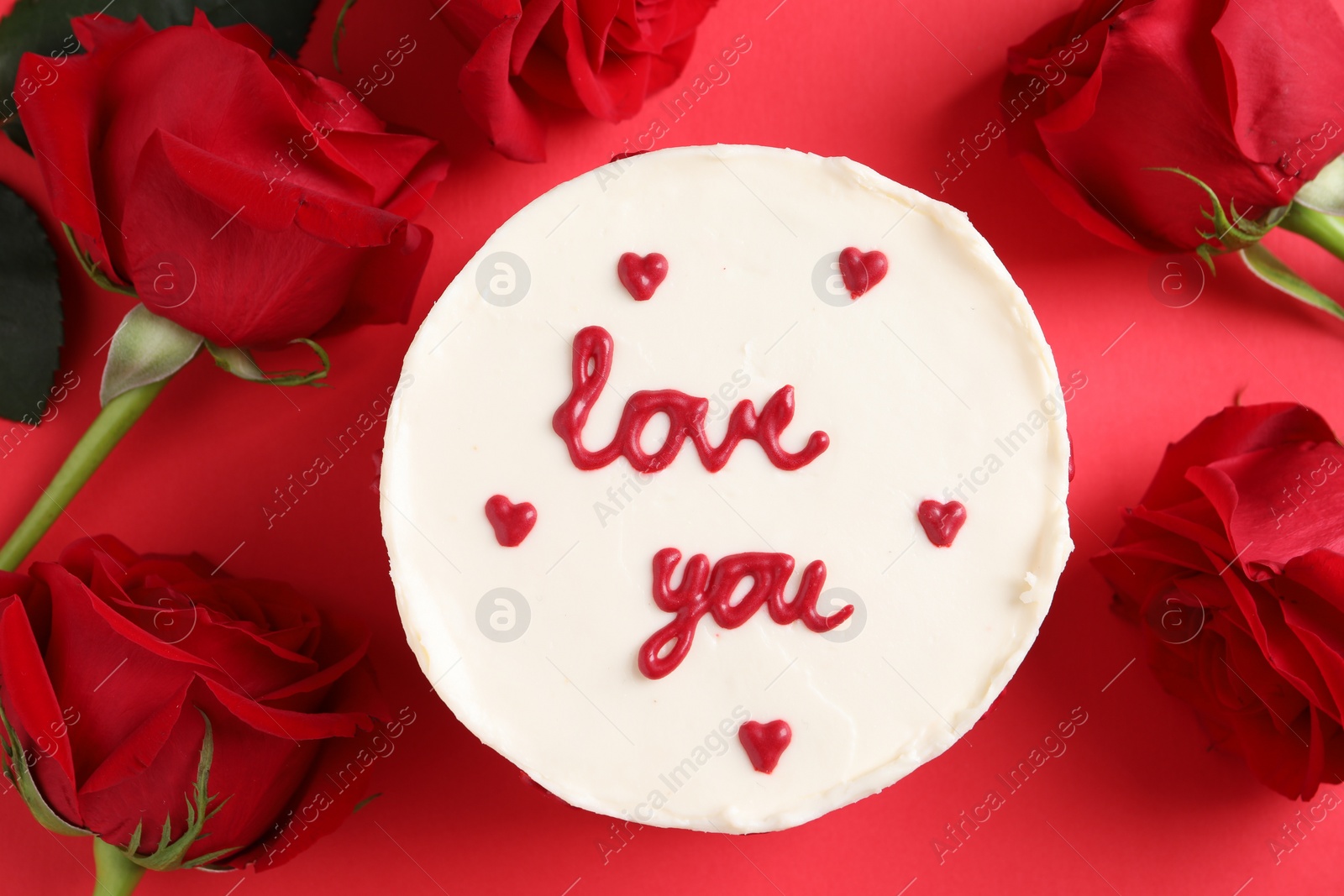 Photo of Bento cake with text Love You and roses on red table, flat lay. St. Valentine's day surprise